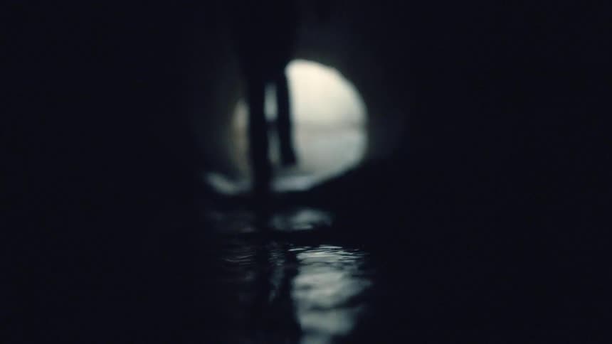 Silhouette of a person walking through a river as the full moon shines