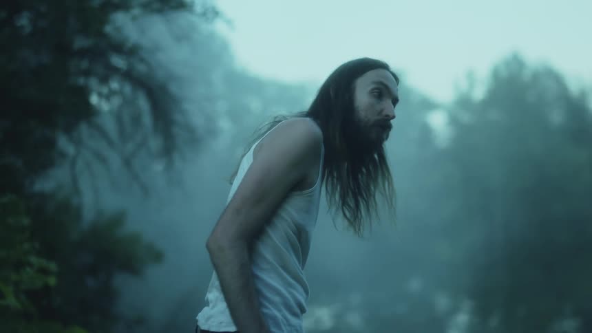A man searches around in the foggy woods