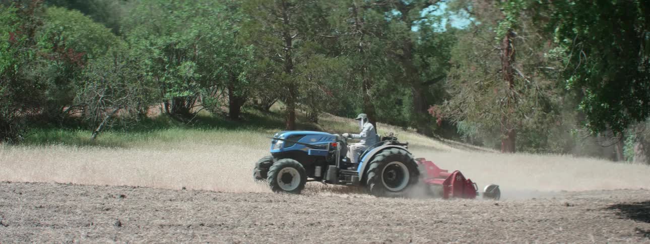 A farmer plowing a dirt field with a tractor