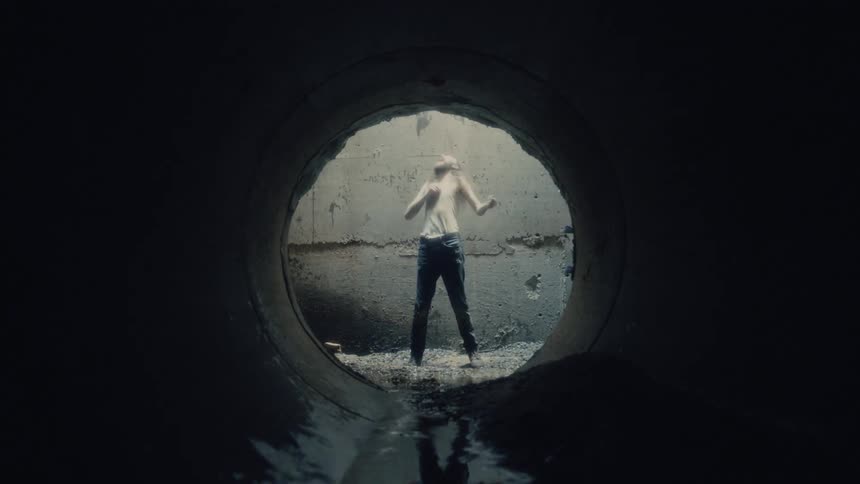 A person is standing by a tunnel during the day and is mad