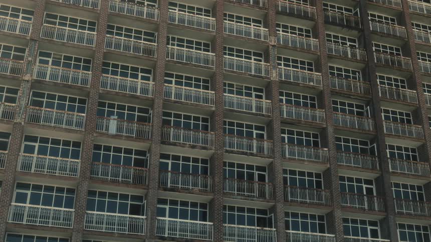 Apartments with identical windows and balconies line the side of a building
