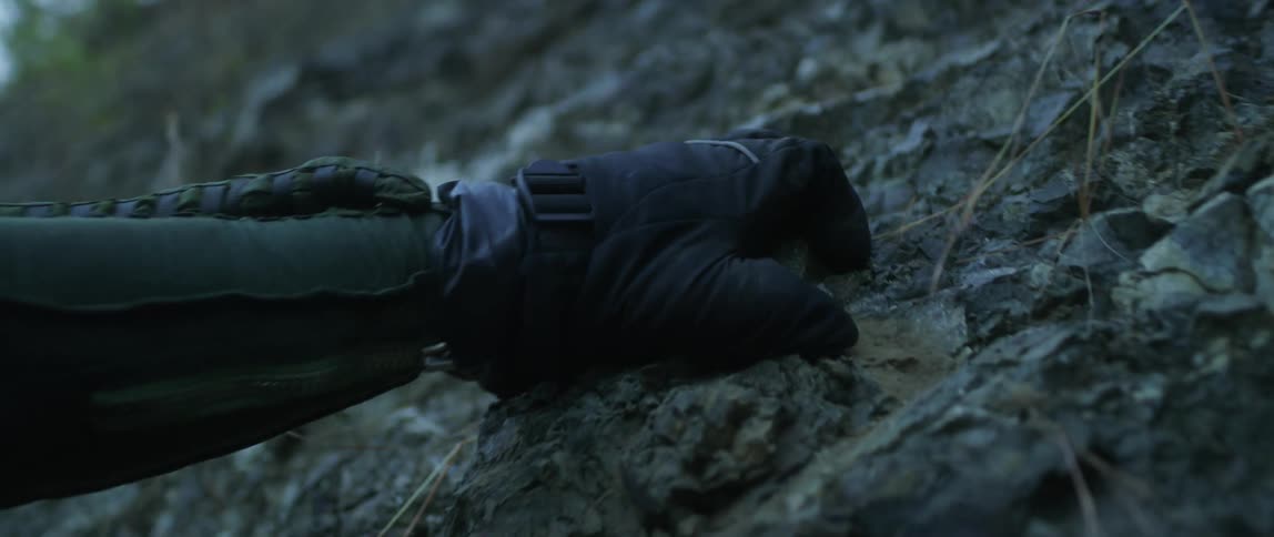 A gloved hand grips tightly on a rock