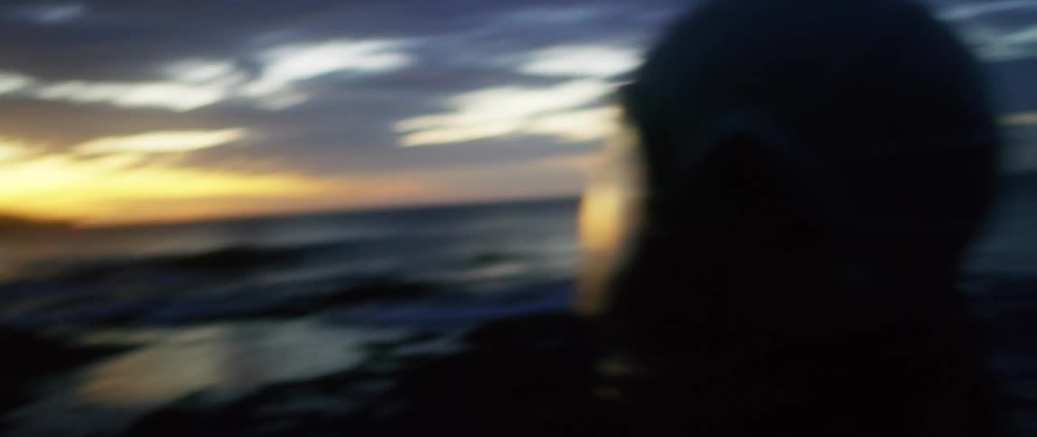 A man is standing outdoors at dusk and wearing a helmet
