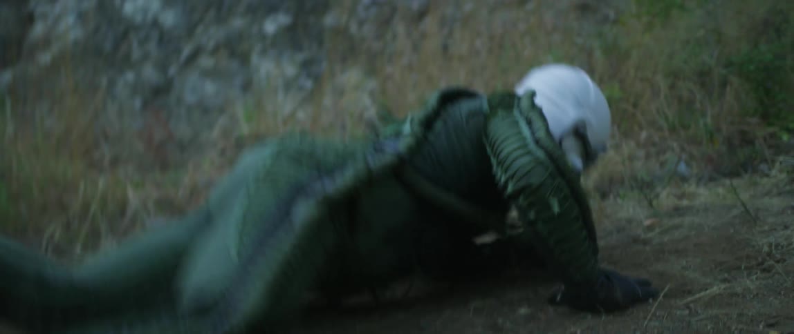 A man in a helmet and bodysuit falling to the ground outdoors