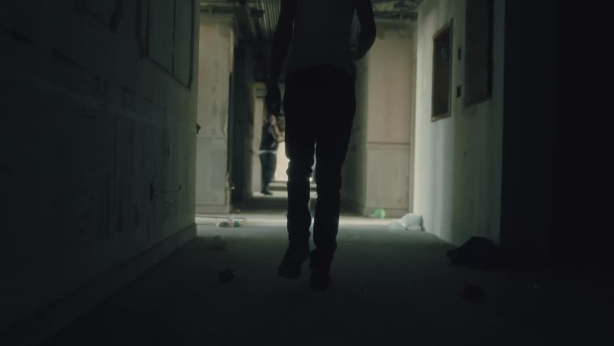 A female wearing tank top is walking in an alleyway