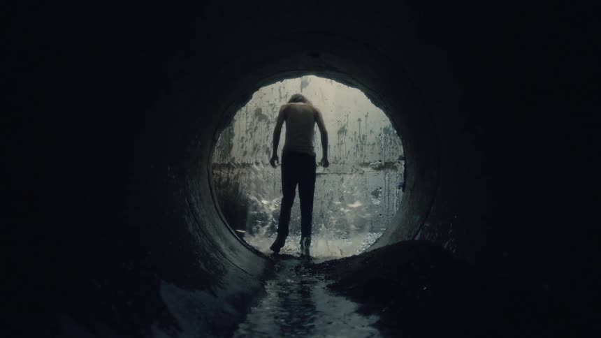 A man is walking angrily through a tunnel