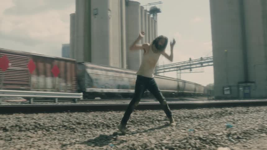A man walks back and forth by a train and yells and throws his arms in the air