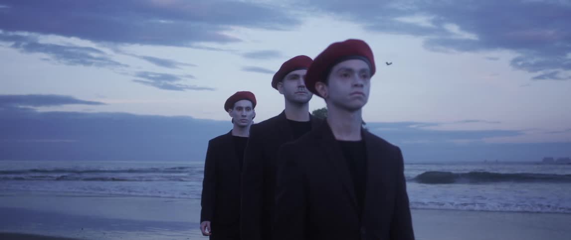 Four men are standing at the beach and wearing hats