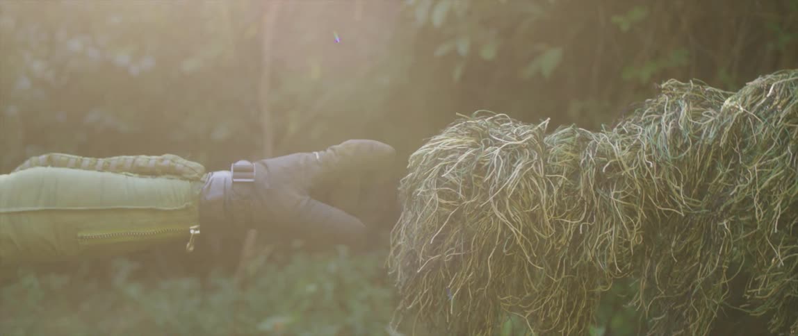 A person that is reaching for hay outdoors in a suit