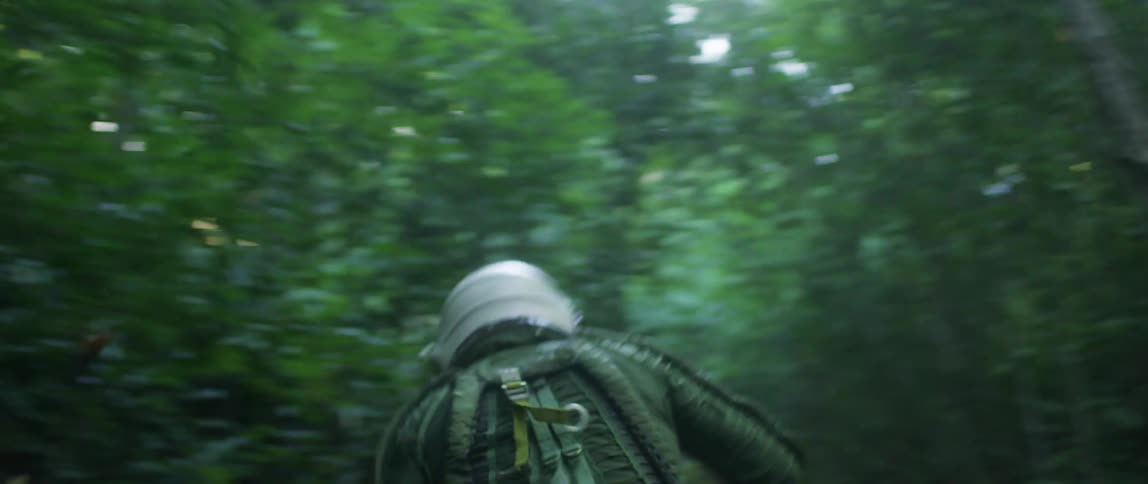 A person with a helmet on runs through a forest in a panic