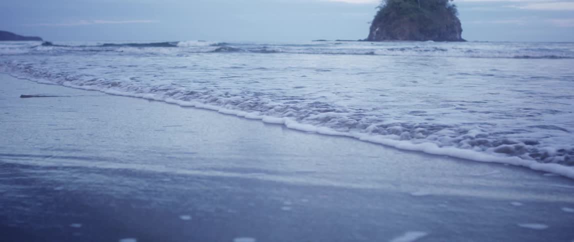 A beach with sand with the ocean sky and clouds in the background