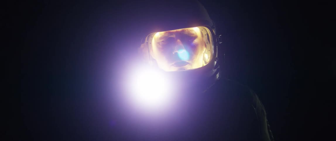 Light glows inside a helmet illuminating a face at night