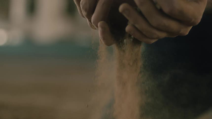 A person on the beach lets sand run through their fingers