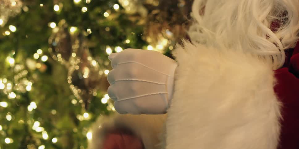 A man dressed up as santa puts gloves on