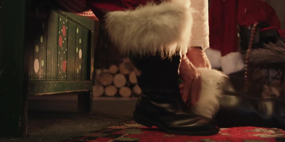 A person dressed as santa claus putting on a black boot