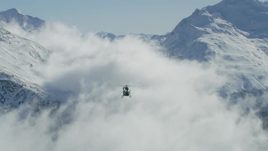 Following a helicopter flying over a snowy mountain range