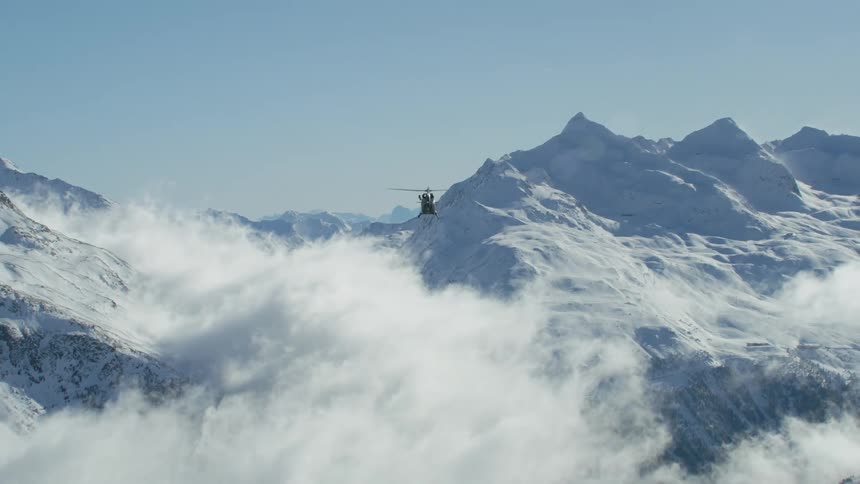 An aerial view of a helicopter flying over mountains