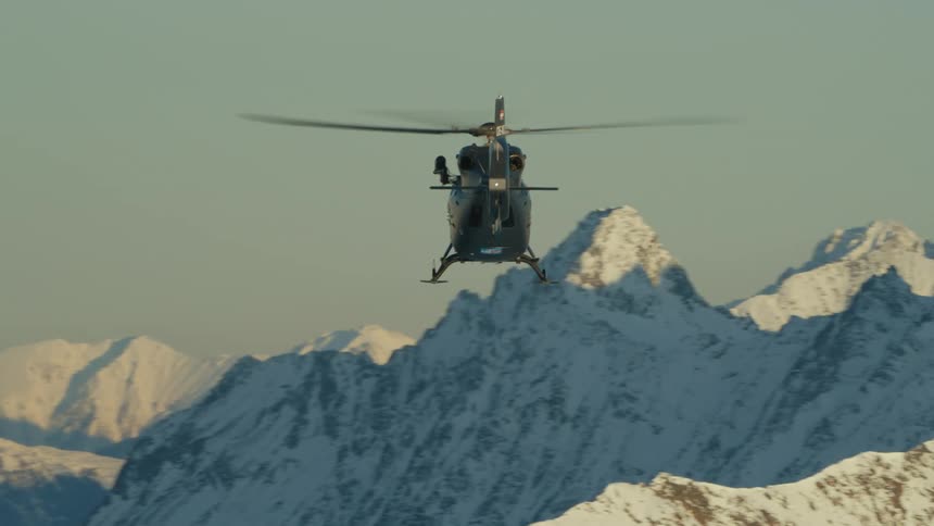 An aerial view of a helicopter flying above mountains