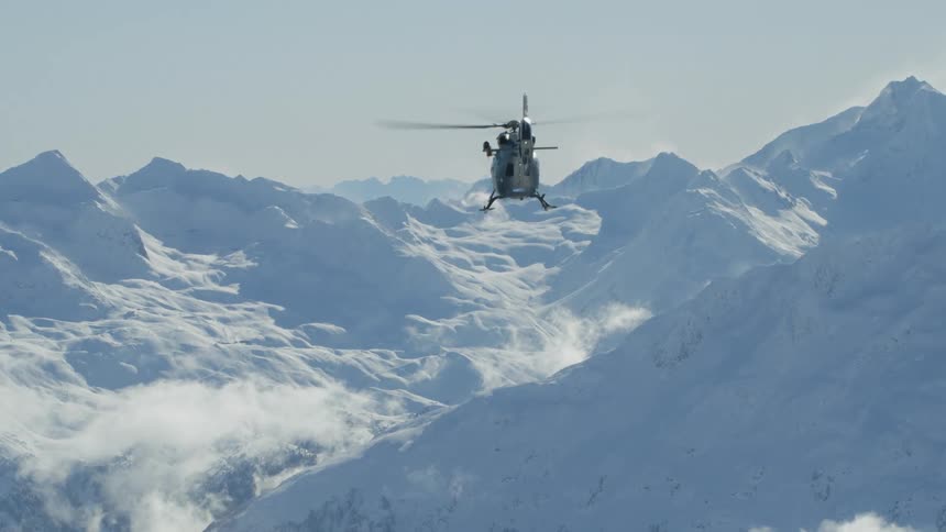 An aerial view of a helicopter flying over mountains