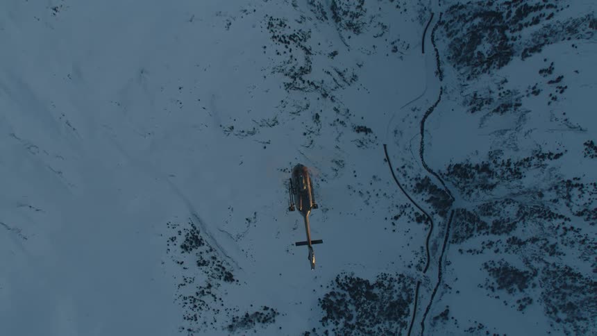 Helicopter flies over the snow covered land