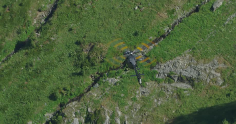 Multicolored rotor forms circular pattern of concentric stripes as helicopter flies over vegetation covered rough terrain partial filled with shadows