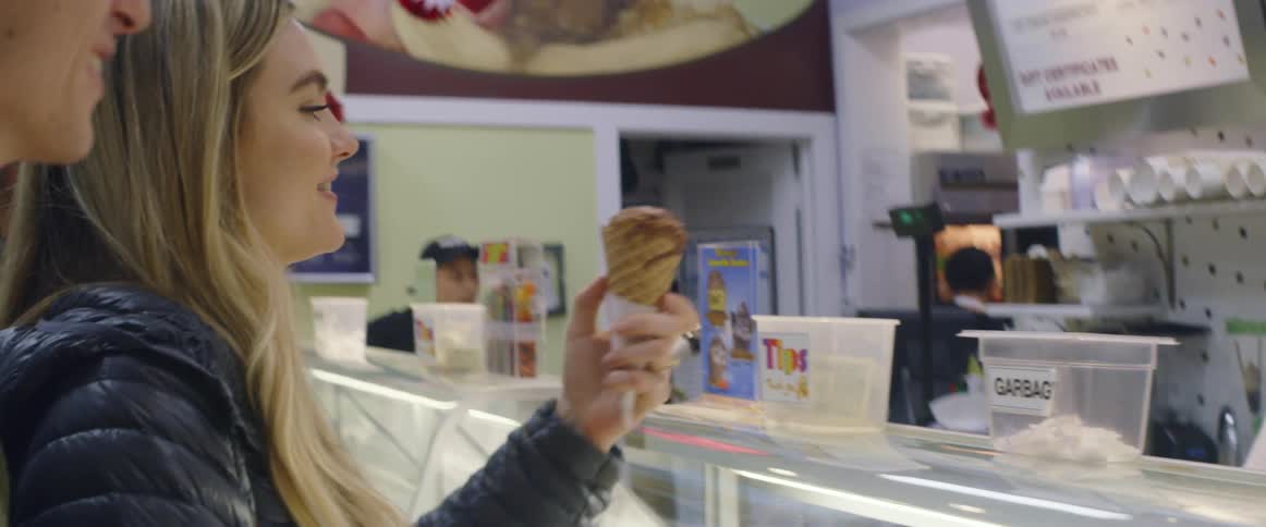 A woman receives an ice cream cone in a shop