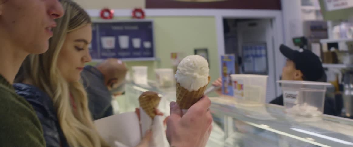 Man taking and licking ice cream cone in ice cream shop