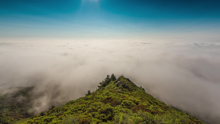 Clouds rolling over a tall grassy mountain