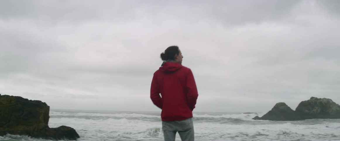 A man on a shore scans a stormy sea