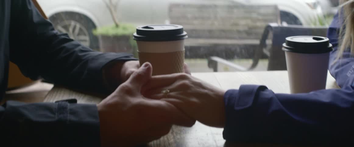 A couple holding hands in a coffee shop