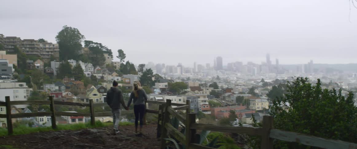 A man and woman walk down a hill holding hands