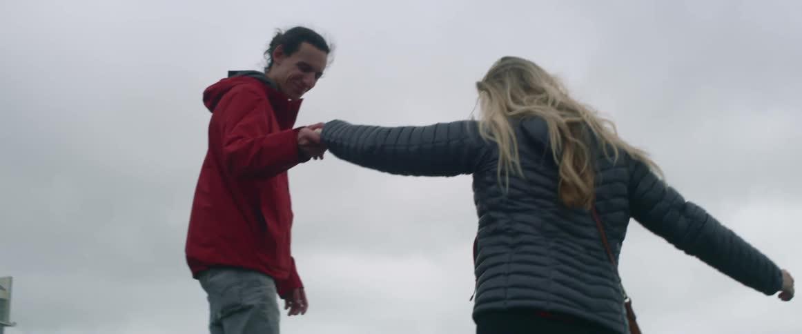 Man helping woman step up onto rocks overlooking the ocean