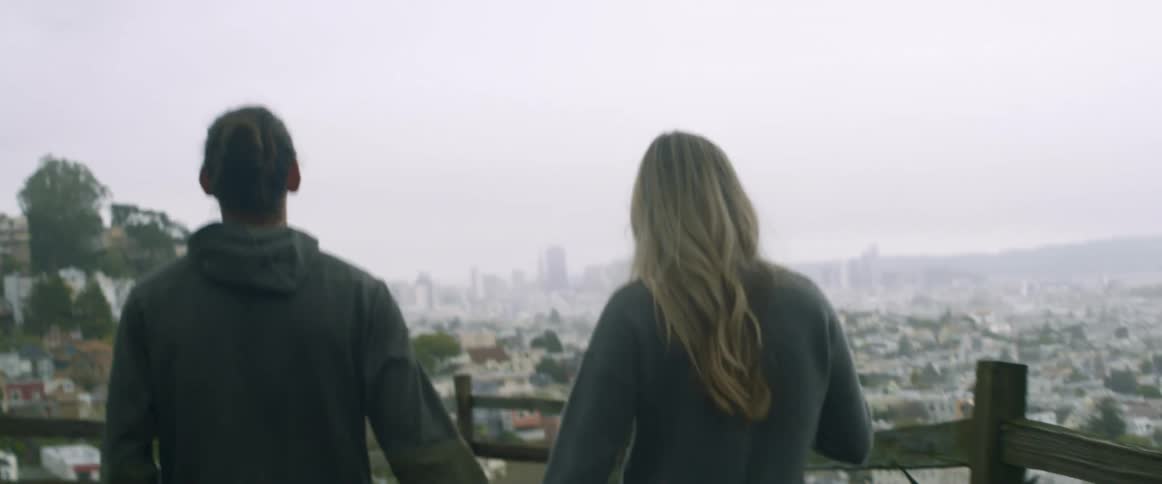 A man and woman hold hands walking on a cloudy day