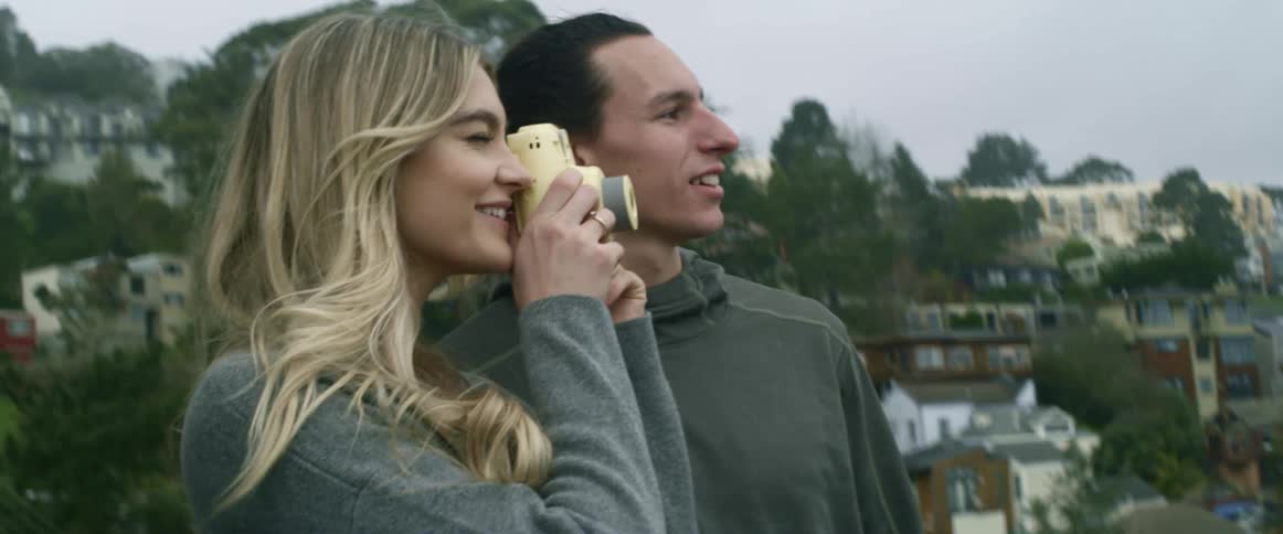 A man stands next to a woman taking pictures