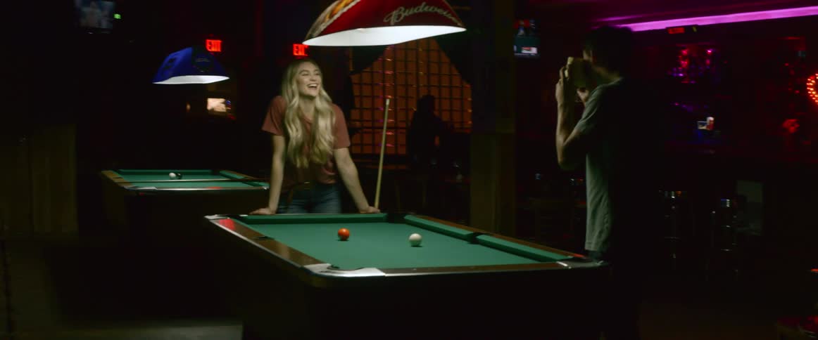 A girl poses for a picture by a pool table