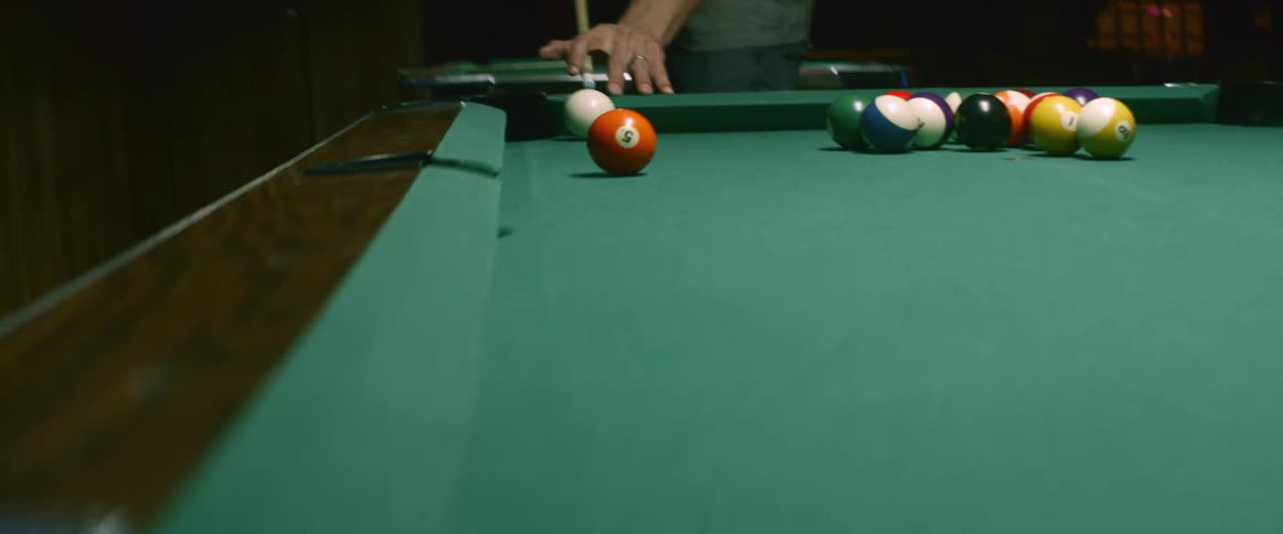 A man takes uses a pool cue to strike a shot