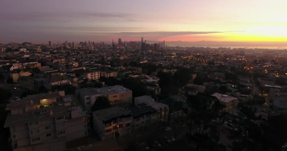 Aerial view coming into a large city at sunset