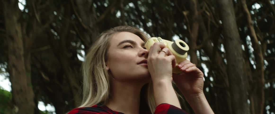 A young woman takes a photo in a forest