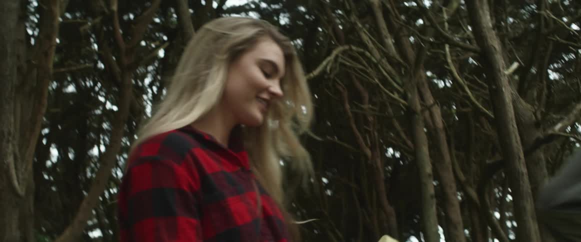 A man and woman walk through the trees and take pictures