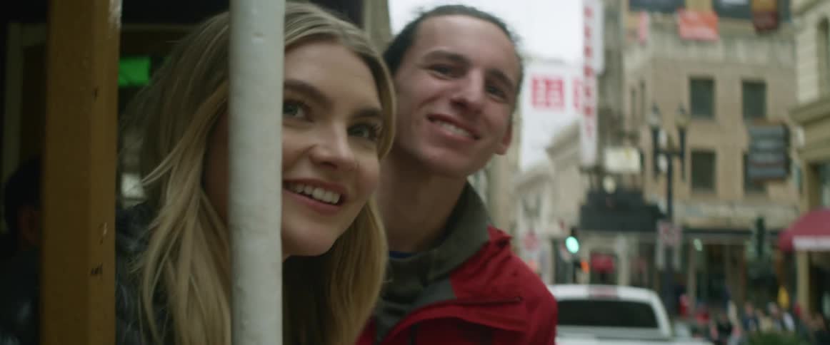 A man and woman ride a trolley looking over the side