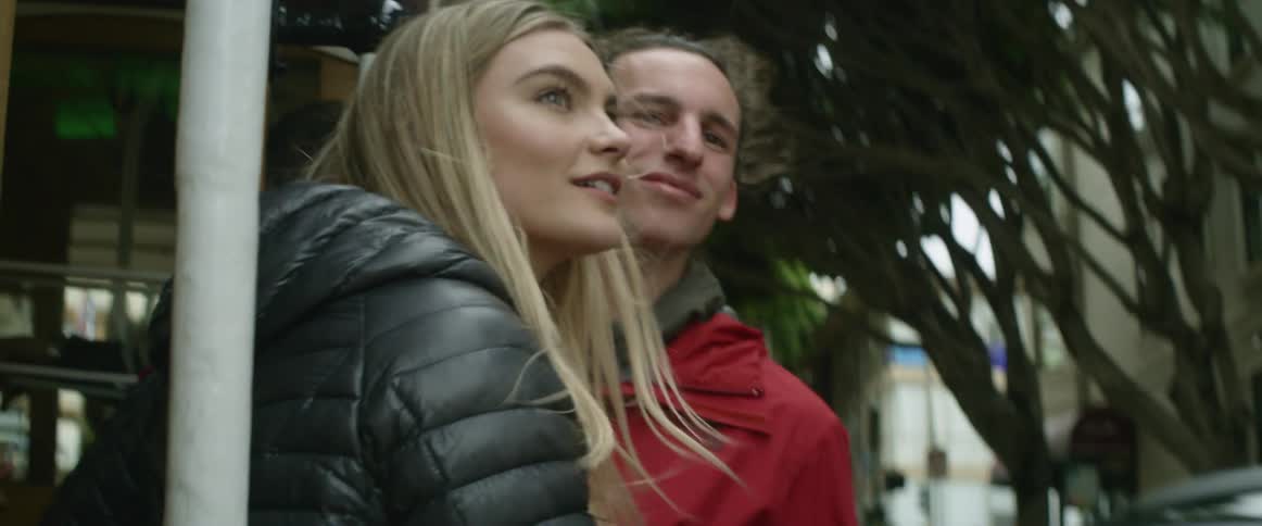 A man and woman lean out of a trolley looking around