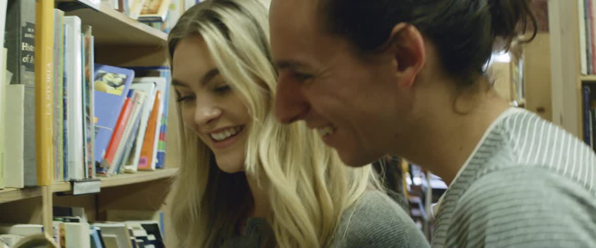 A man and woman are examining books in a library