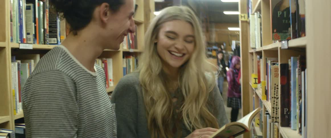 A man and woman examine books in a library
