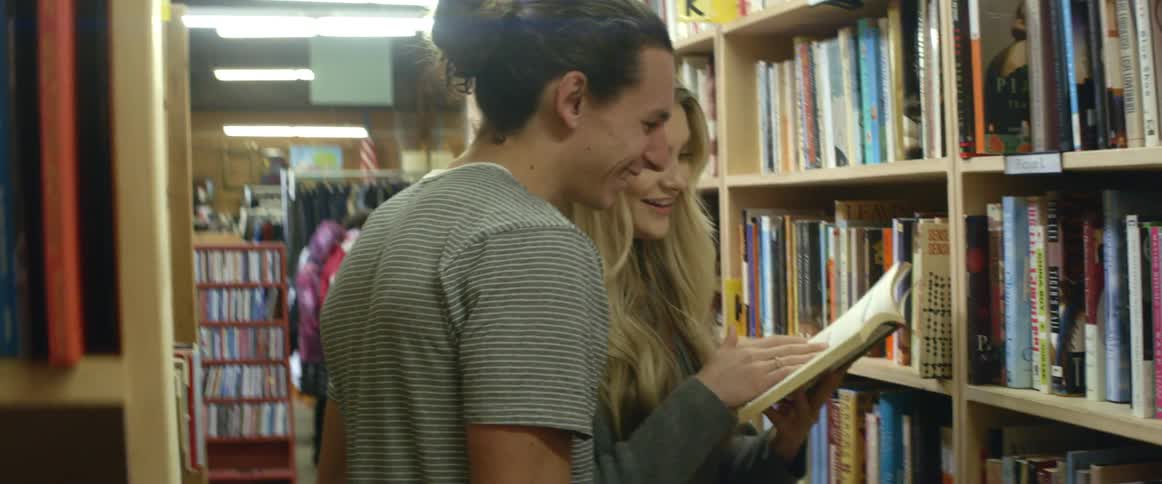 A man and woman look at a book in a library