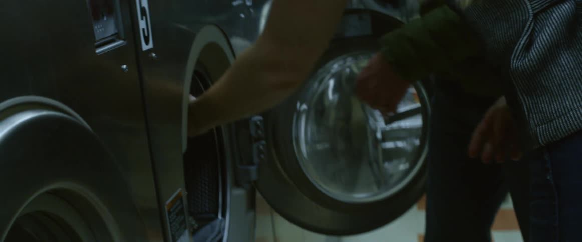 Two people put laundry into a machine together