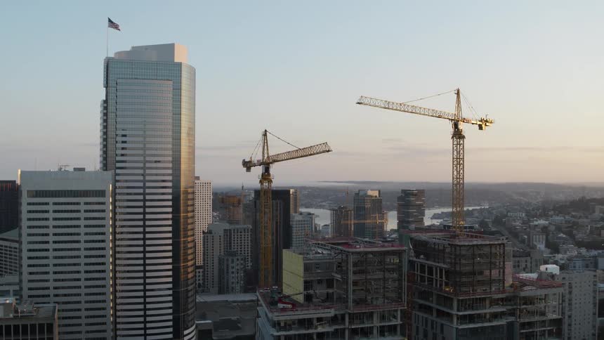 Orbit around two cranes at a highrise construction project near other skyscrapers