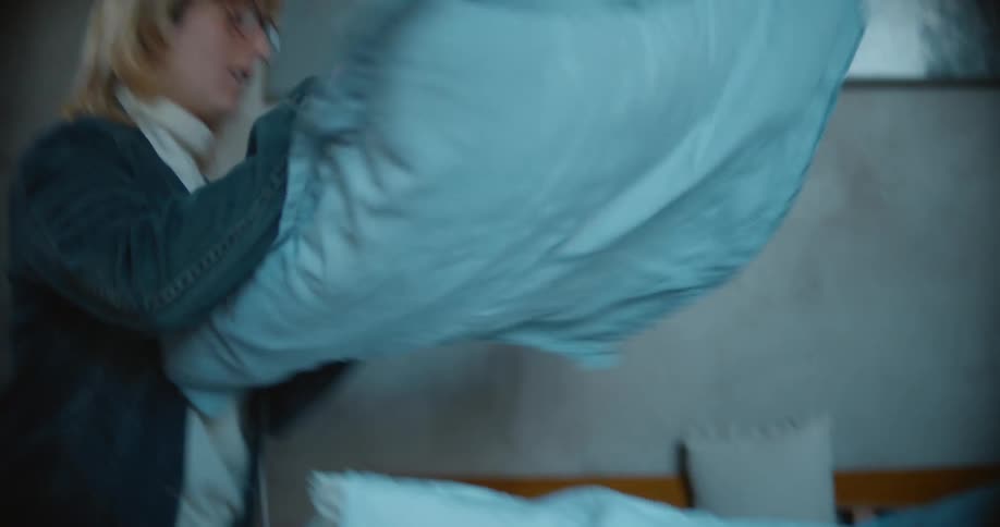 A woman putting pillows on a bed
