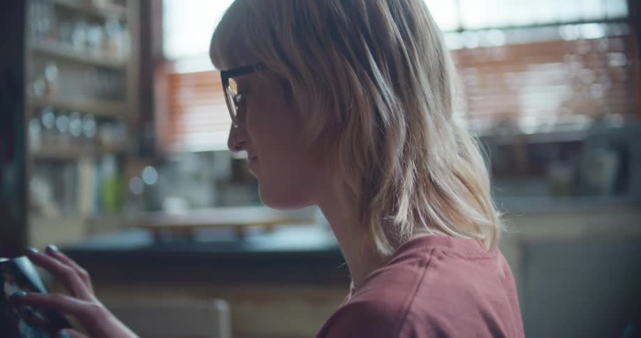 Blonde woman sits at table looking through printed photographs
