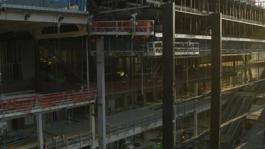 Traverse along the steel beam framework of a large and complex building construction site