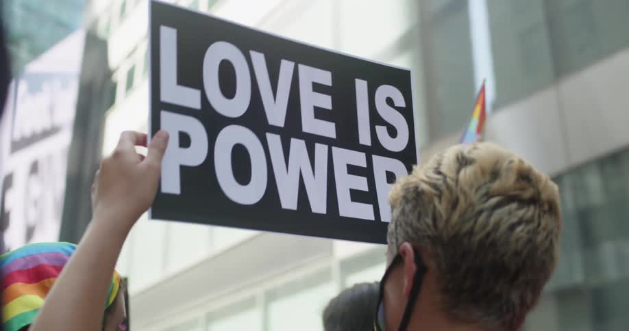 Group of people participate in a march in the city as one holds up a sign